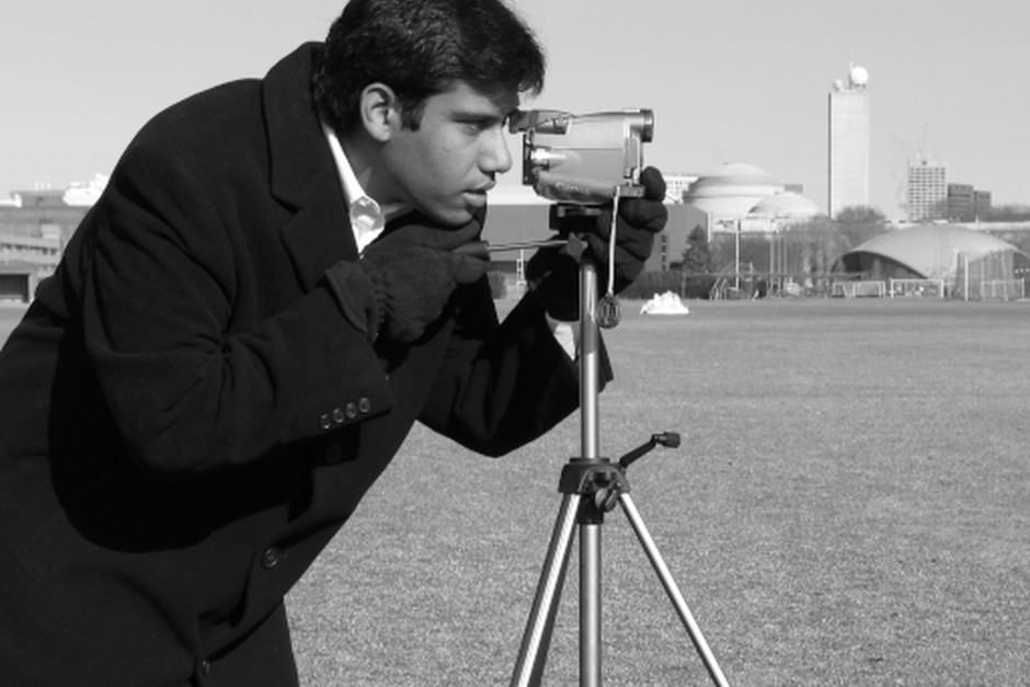 A photographer using a camera on a tripod outdoors.